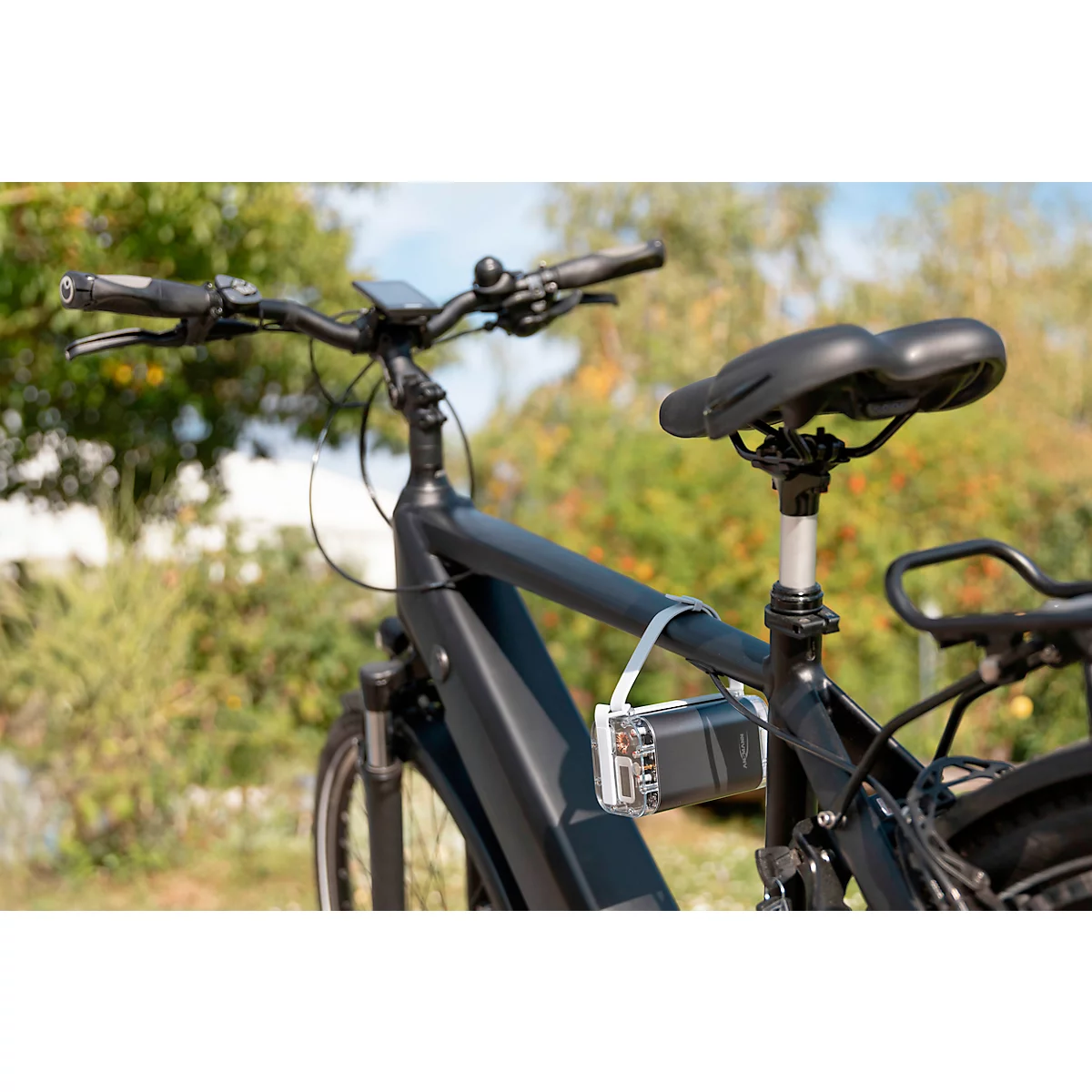 Zwarte e-bike buiten, met een accu aan het frame bevestigd. De fiets wordt in detail getoond, de achtergrond is vervaagd.