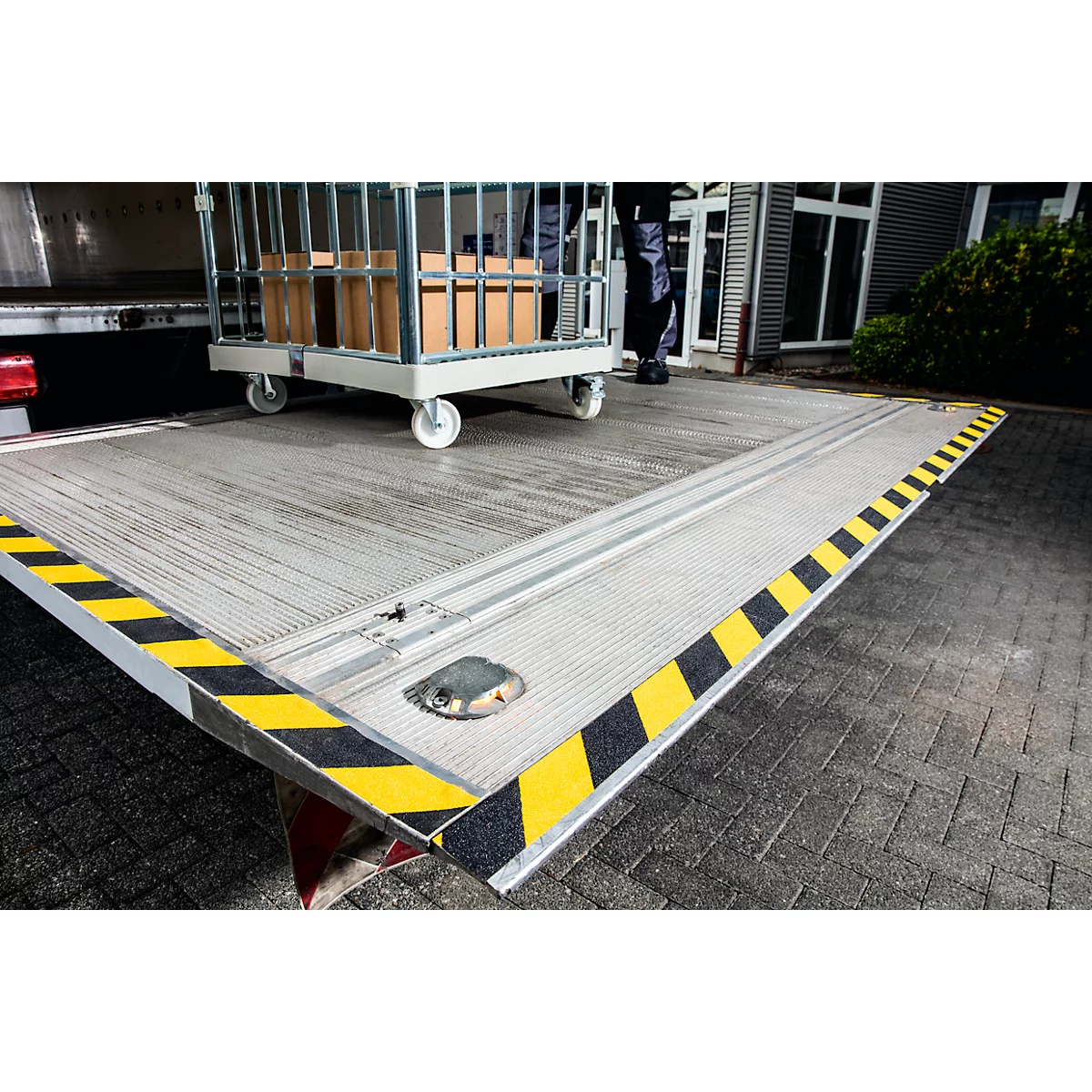Loading ramp with trolley and boxes. Yellow and black markings on the edge.