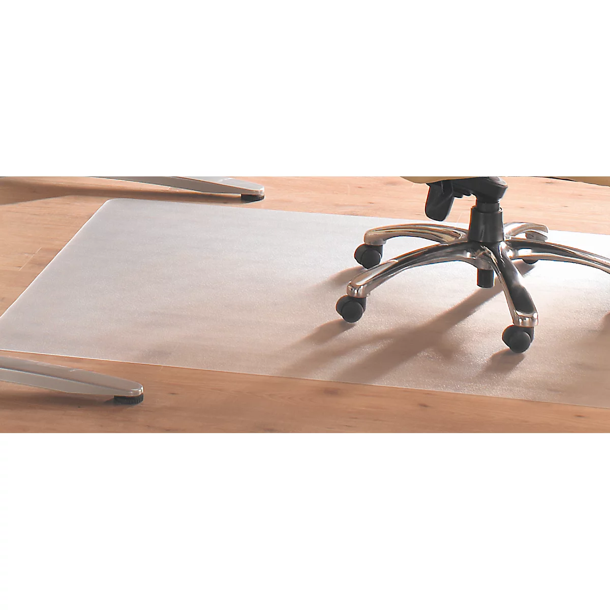 Durchsichtige Bürostuhlunterlage auf Holzboden unter einem Stuhl. Der Stuhl hat fünf Rollen.