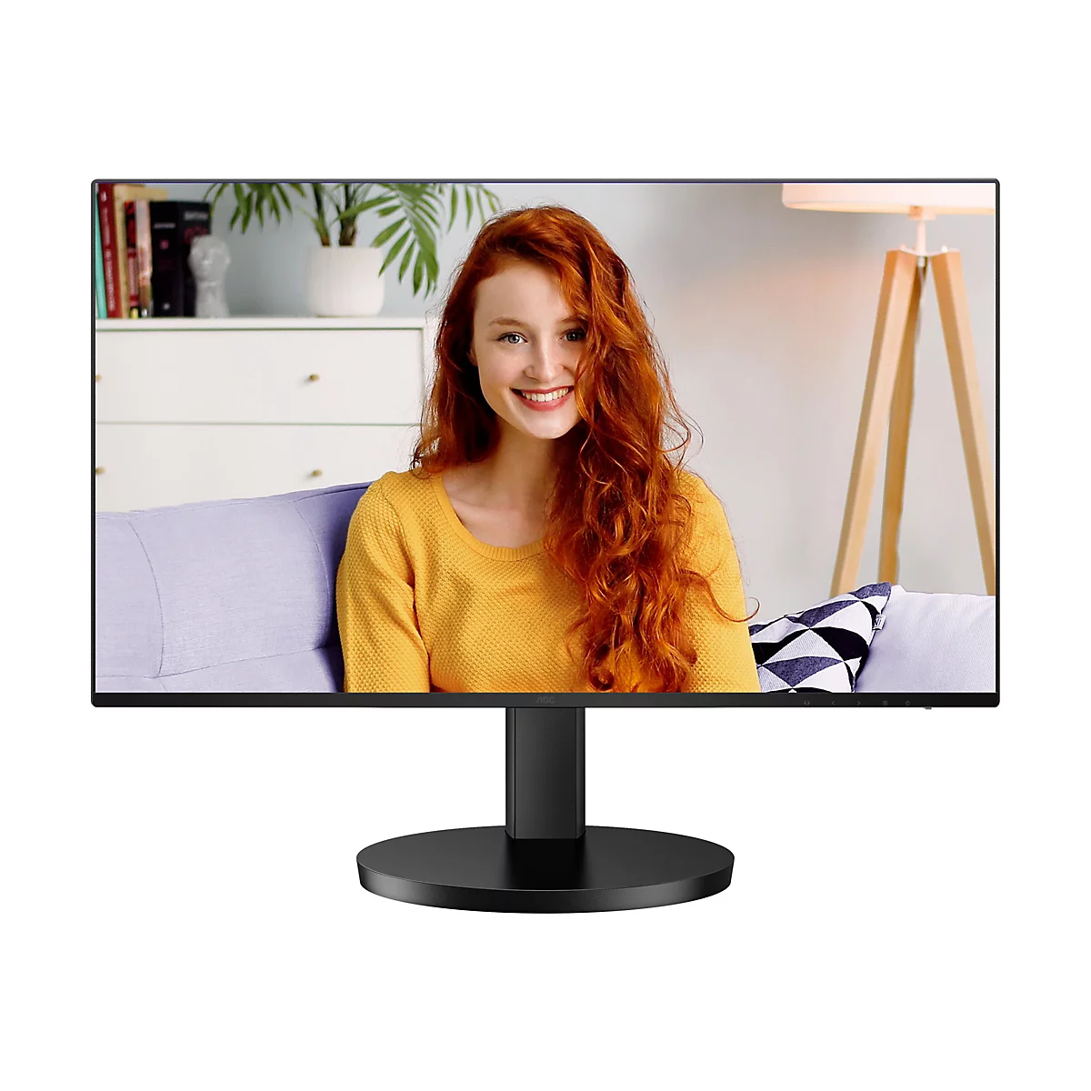 Ein schwarzer Monitor zeigt eine junge, rothaarige Frau, die lächelt. Sie trägt einen gelben Pullover. Im Hintergrund sind Wohnaccessoires zu sehen.