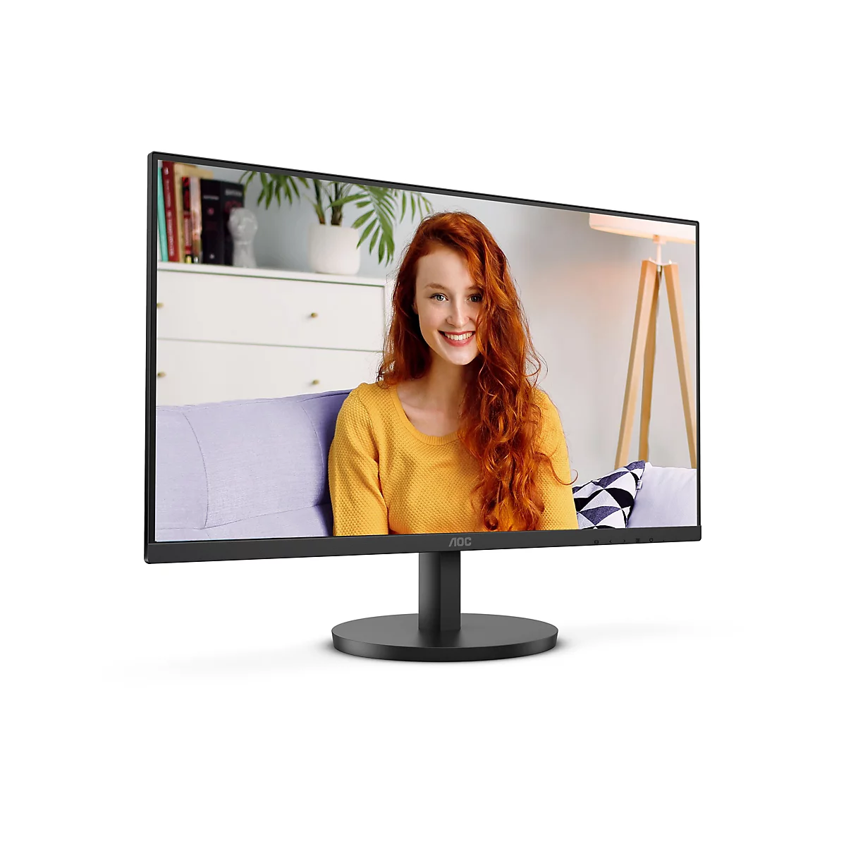 Ein AOC Monitor zeigt eine lächelnde Frau mit roten Haaren. Sie sitzt auf einem Sofa und trägt einen gelben Pullover. Das Bild im Monitor zeigt ein Zimmer.