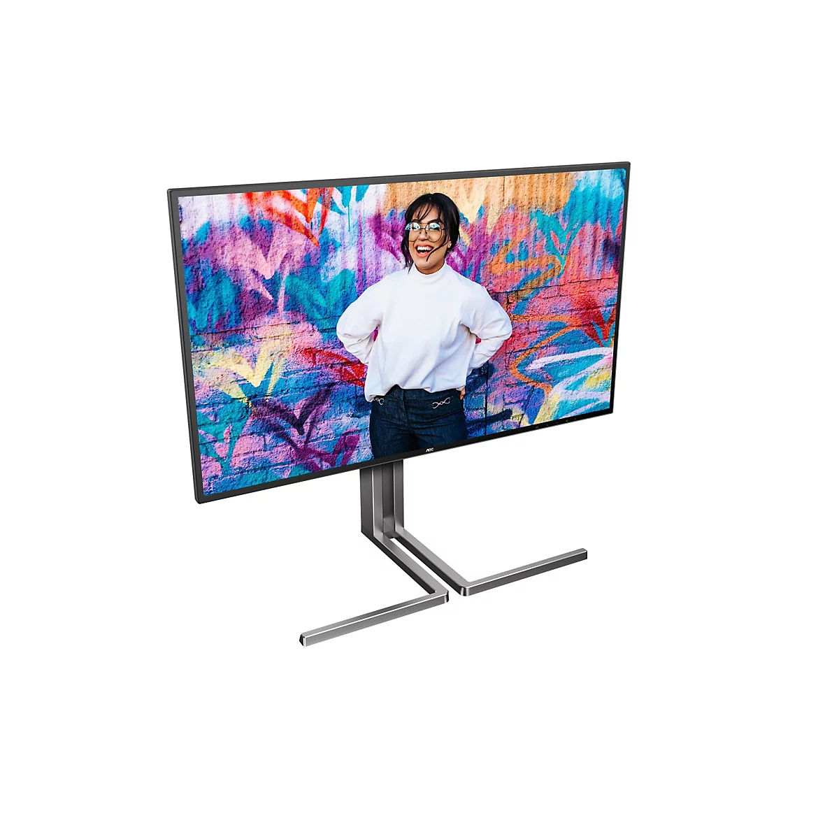 Ein großer Monitor zeigt ein Bild einer lachenden Frau vor einer bunten Graffiti-Wand. Der Monitor steht auf einem silberfarbenen Ständer.