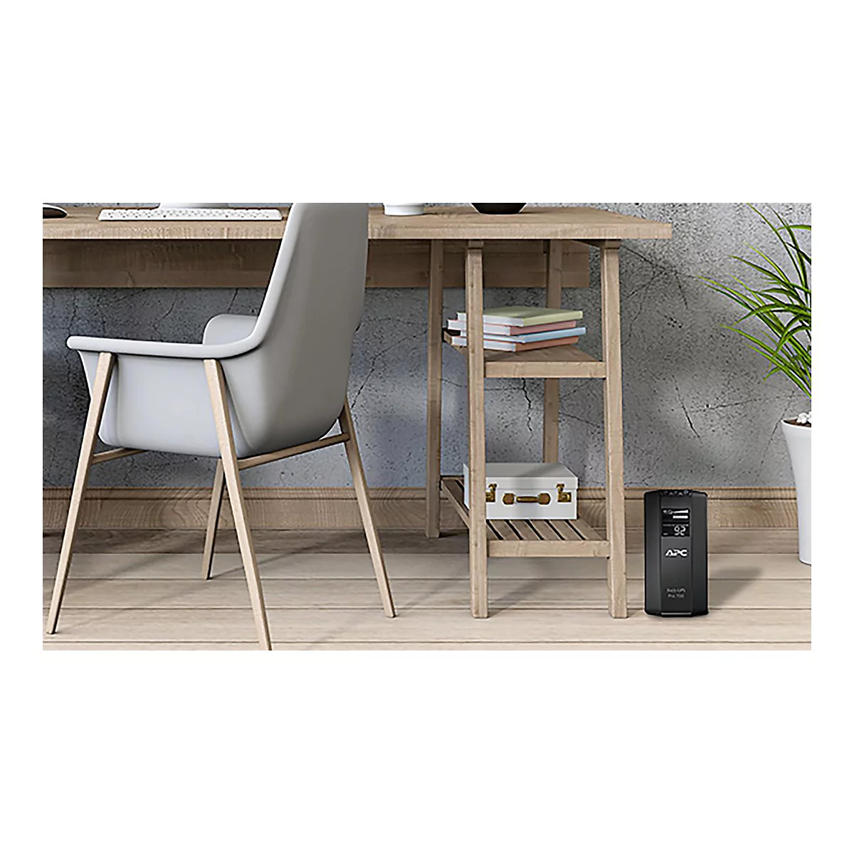 Bureau avec chaise, petite étagère et onduleur APC. Livres et un coffre sur l'étagère. Une plante à droite.