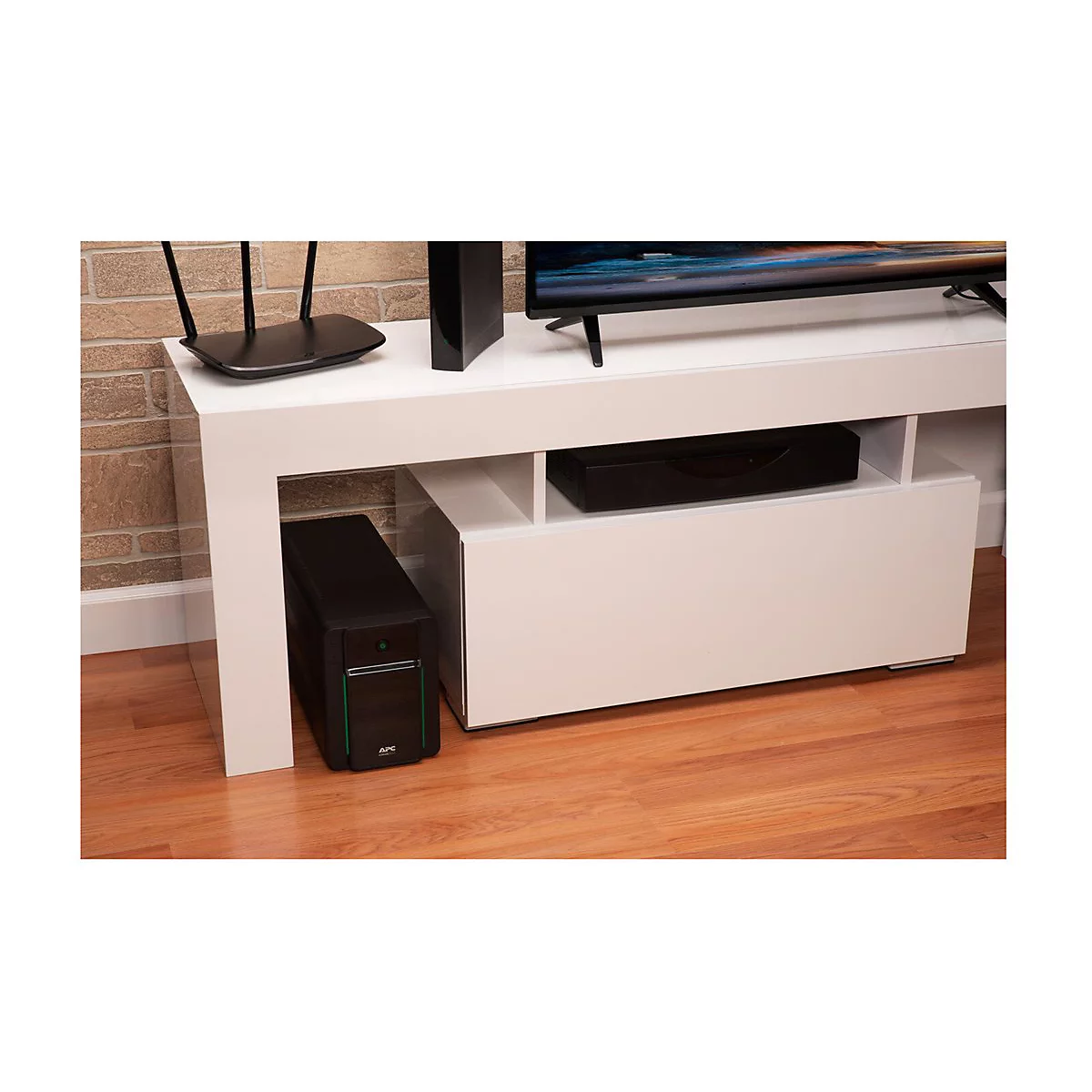 Weiße TV-Bank mit TV, Router, Soundbar, USV. Auf Holzfußboden stehend.