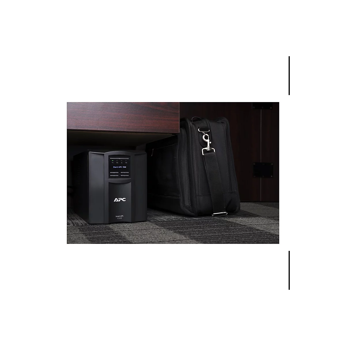 Onduleur noir sous une armoire, à côté d'un sac messager noir.