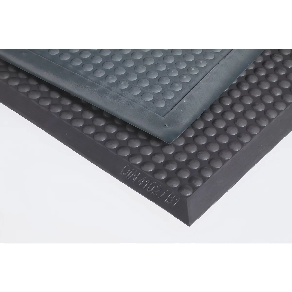 Nahaufnahme einer schwarzen Gummimatte mit Noppenstruktur und eingeprägter Aufschrift DIN 4102/B1.