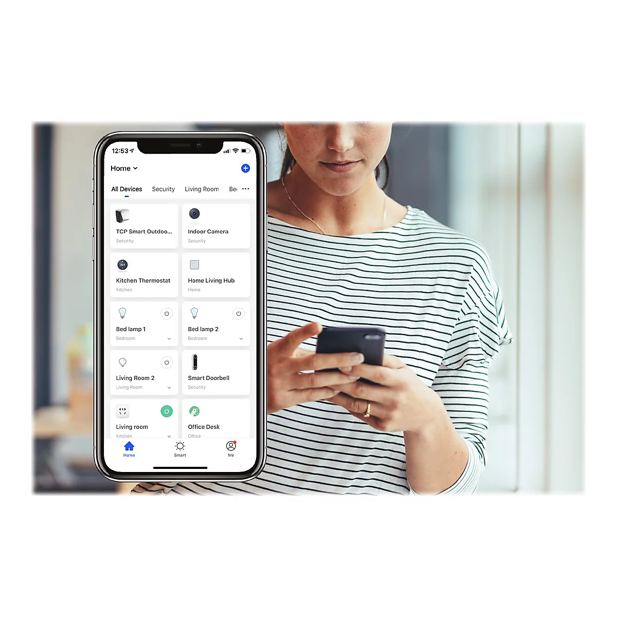 Une femme tient un smartphone et contrôle des appareils domestiques intelligents via une application.