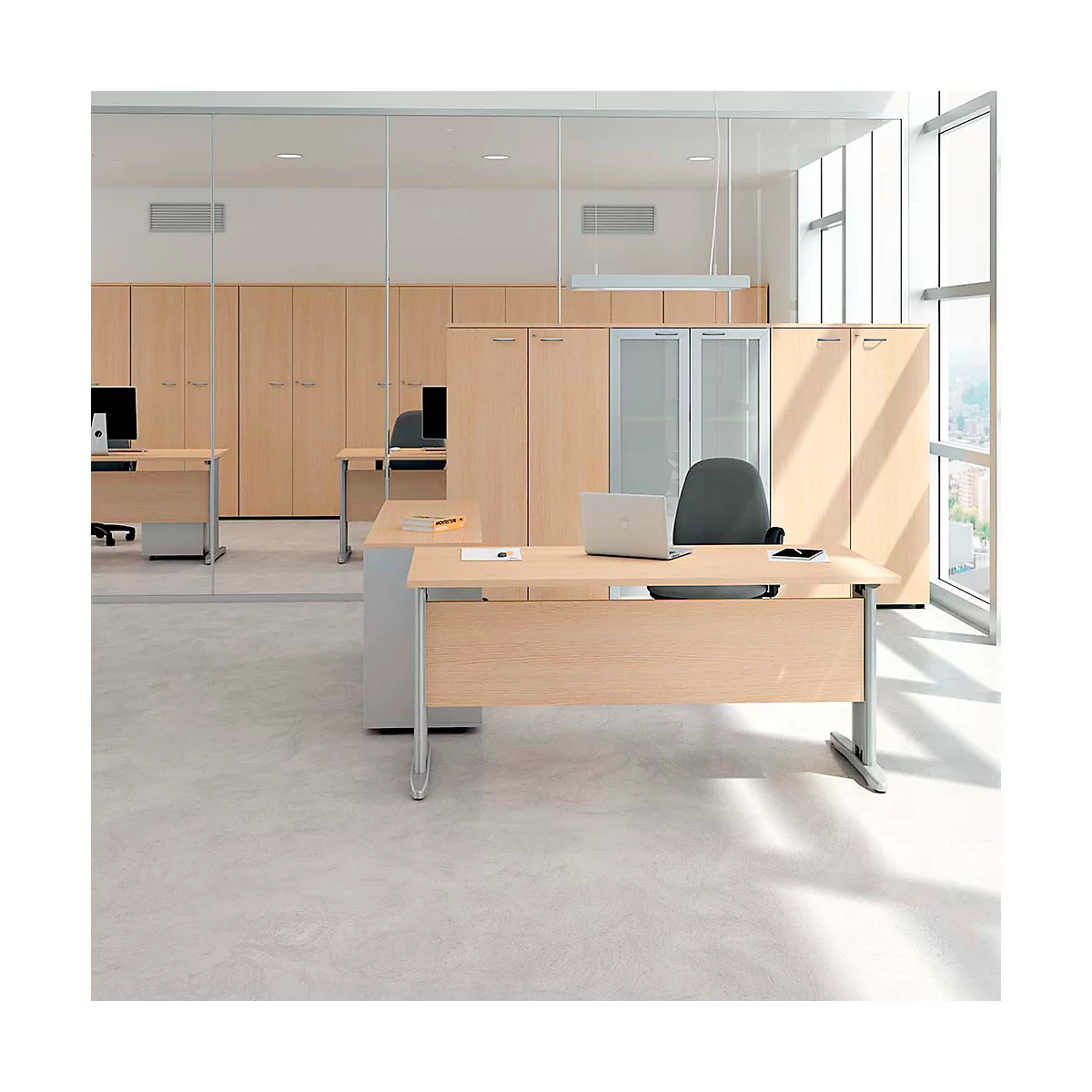 Office with wooden desks, chairs, cabinets, and a laptop. Bright, modern setting with large windows.