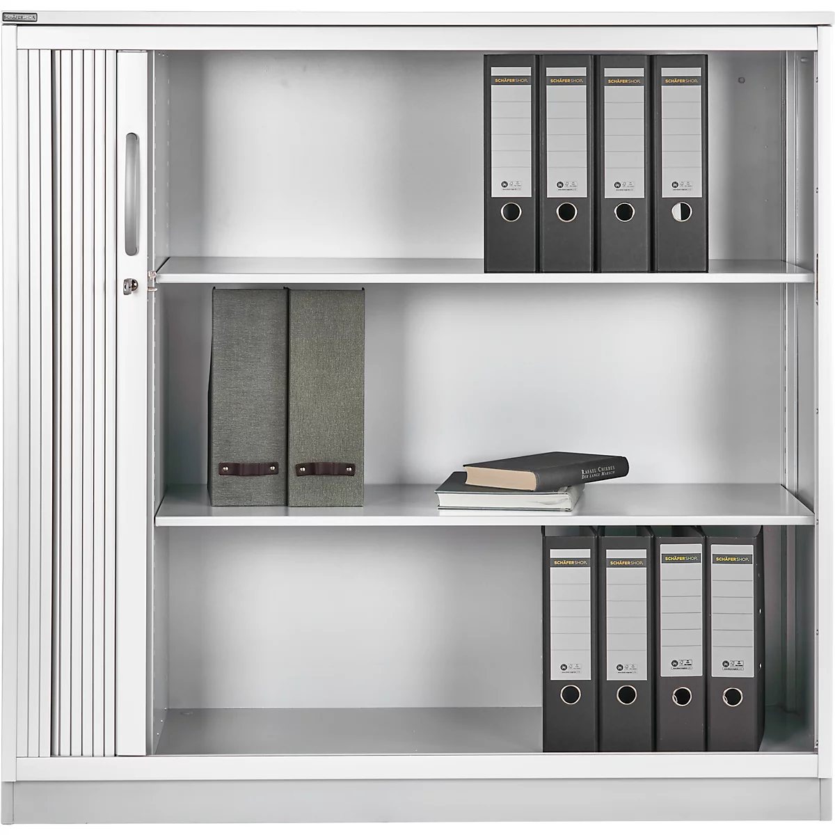 Archivo blanco con puerta de lamas, varios estantes y carpetas. Hay un libro en un estante.
