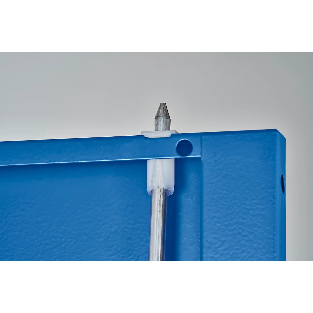 Gros plan d'une tige métallique fixée à une plaque métallique bleue par un support en plastique blanc.