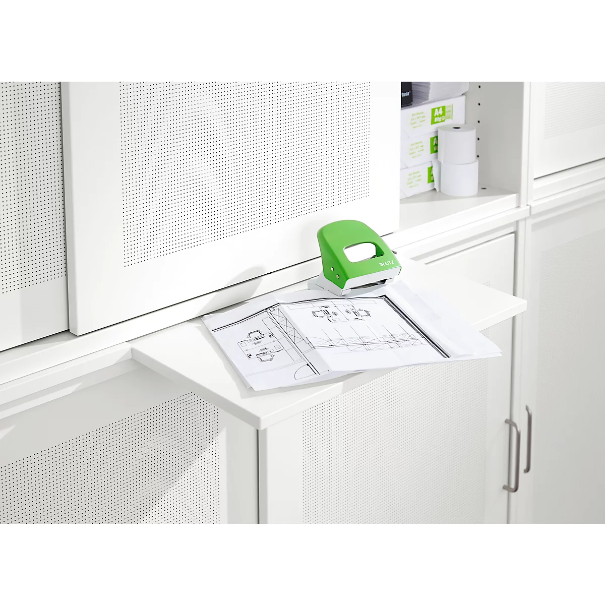 Un tampon vert est posé sur une extension blanche sur laquelle se trouve un plan de construction. Dans le fond, une armoire blanche.