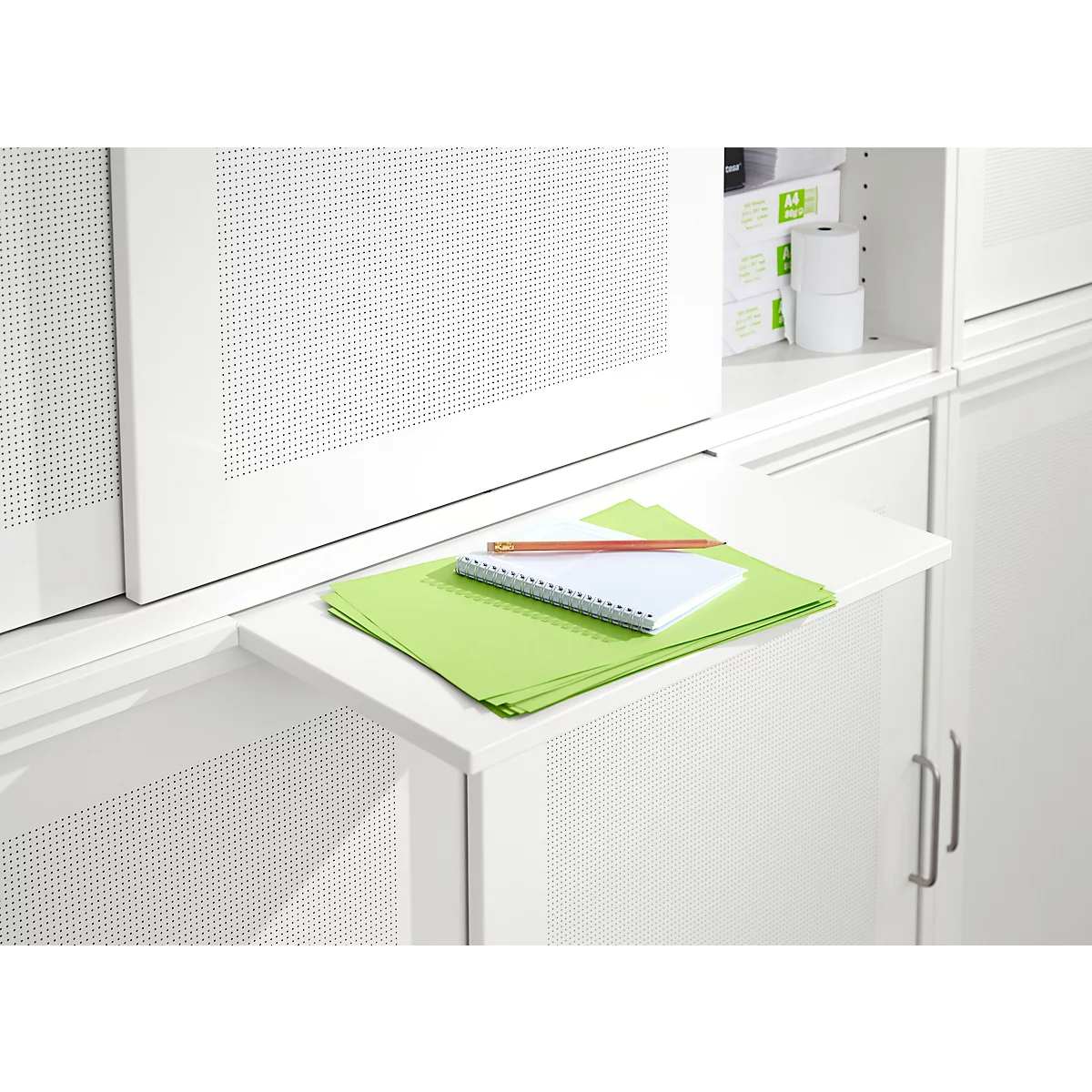 Du papier vert, un bloc-notes et un crayon reposent sur une étagère blanche coulissante. Le fond est blanc.