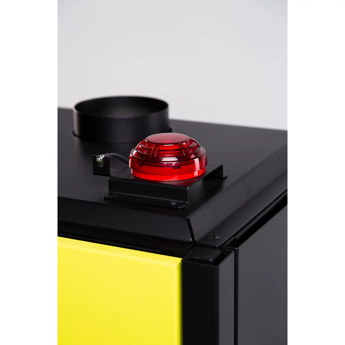 Gros plan sur un poêle avec une lumière rouge. Élément jaune à gauche, élément noir à droite, conduit de fumée noir.