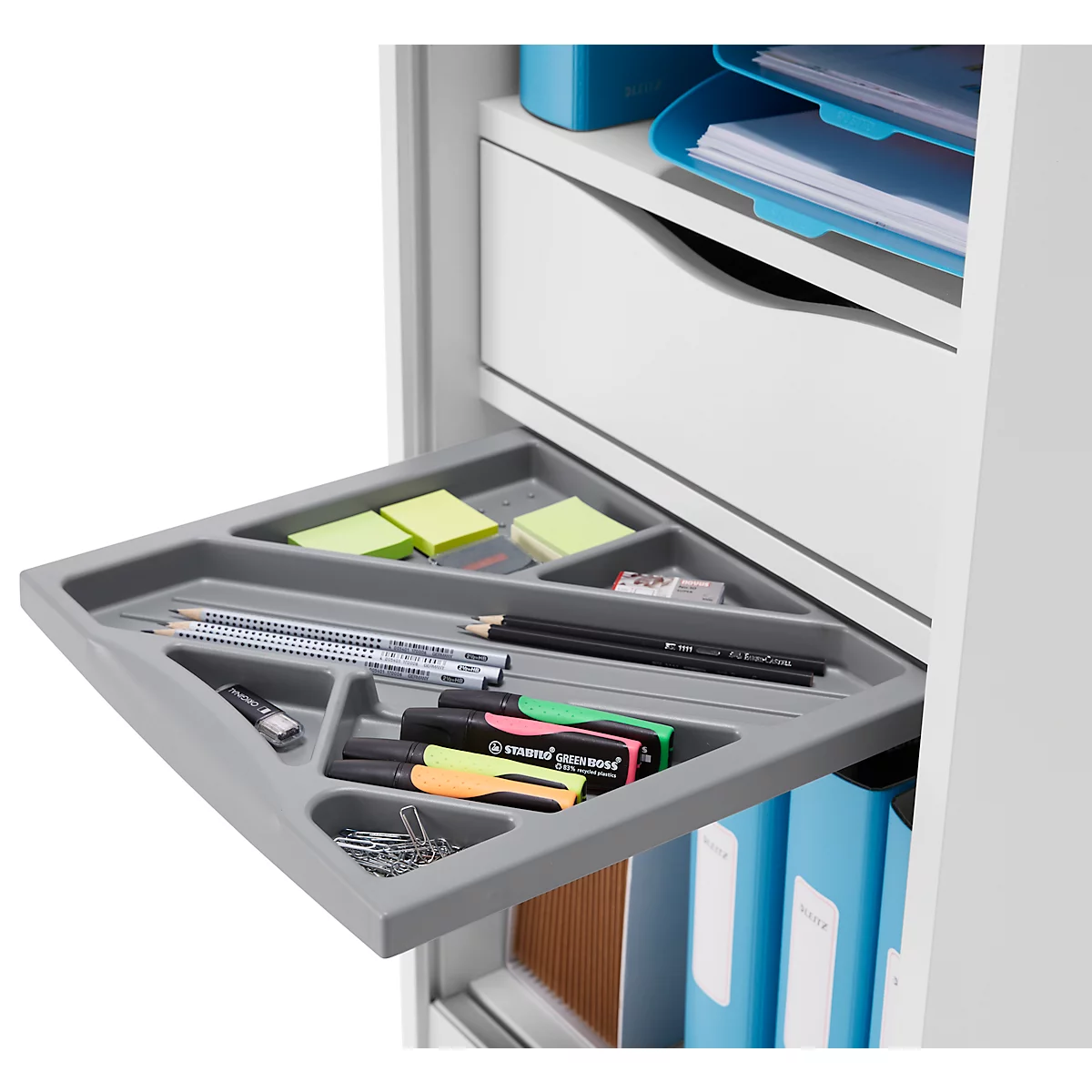 Étagère d'angle grise et coulissante avec stylos, post-it, marqueurs et trombones.