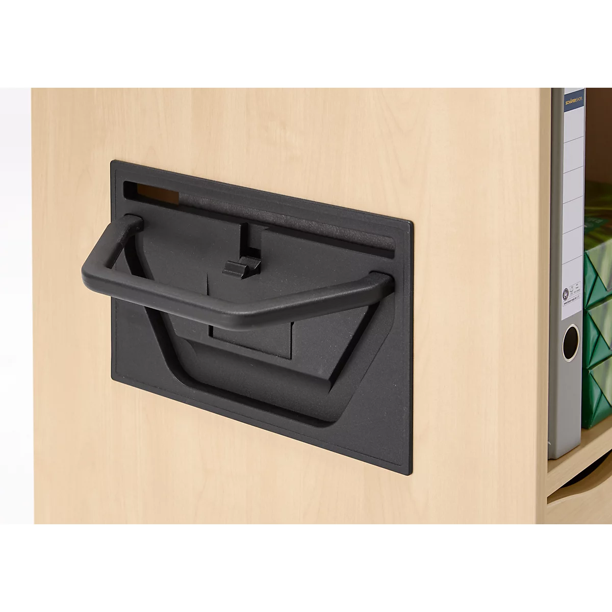 Poignée noire sur une porte d'armoire en bois clair. La poignée est tirée.