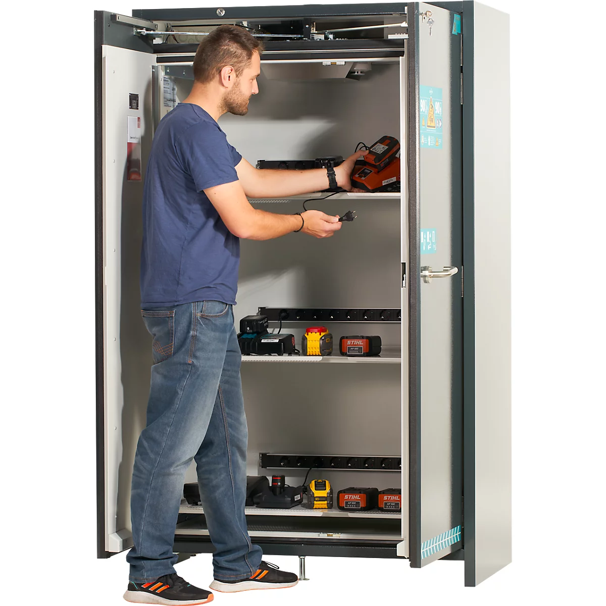 Ein Schrank mit offenen Türen, gefüllt mit verschiedenen Werkzeugen und Geräten, darunter Ladegeräte, Lampen und Messwerkzeuge.