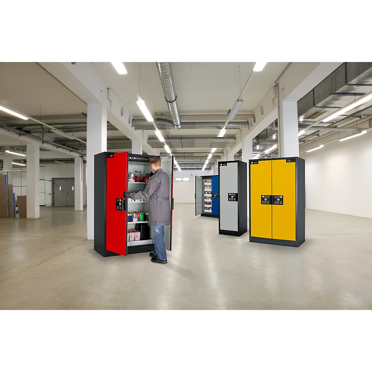 Man opent een rode kast in een werkplaats. Gele, blauwe en grijze kasten staan 