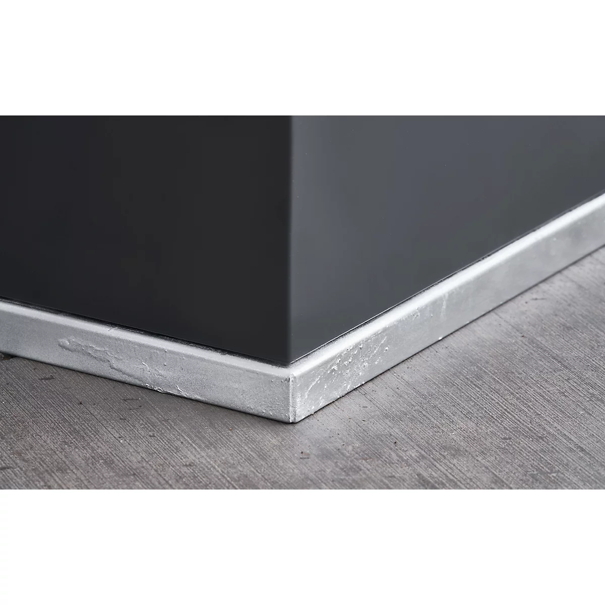 Corner with dark gray wall, baseboard, and wooden floor.