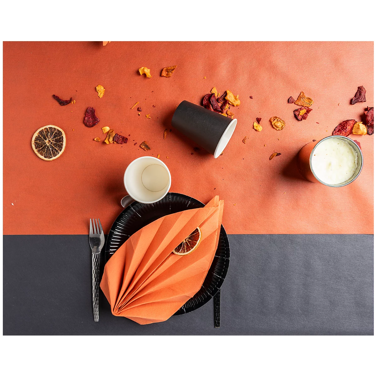 Vue de dessus de la table dressée : assiette noire avec serviettes, tasses, citrons verts, fourchette et collations.