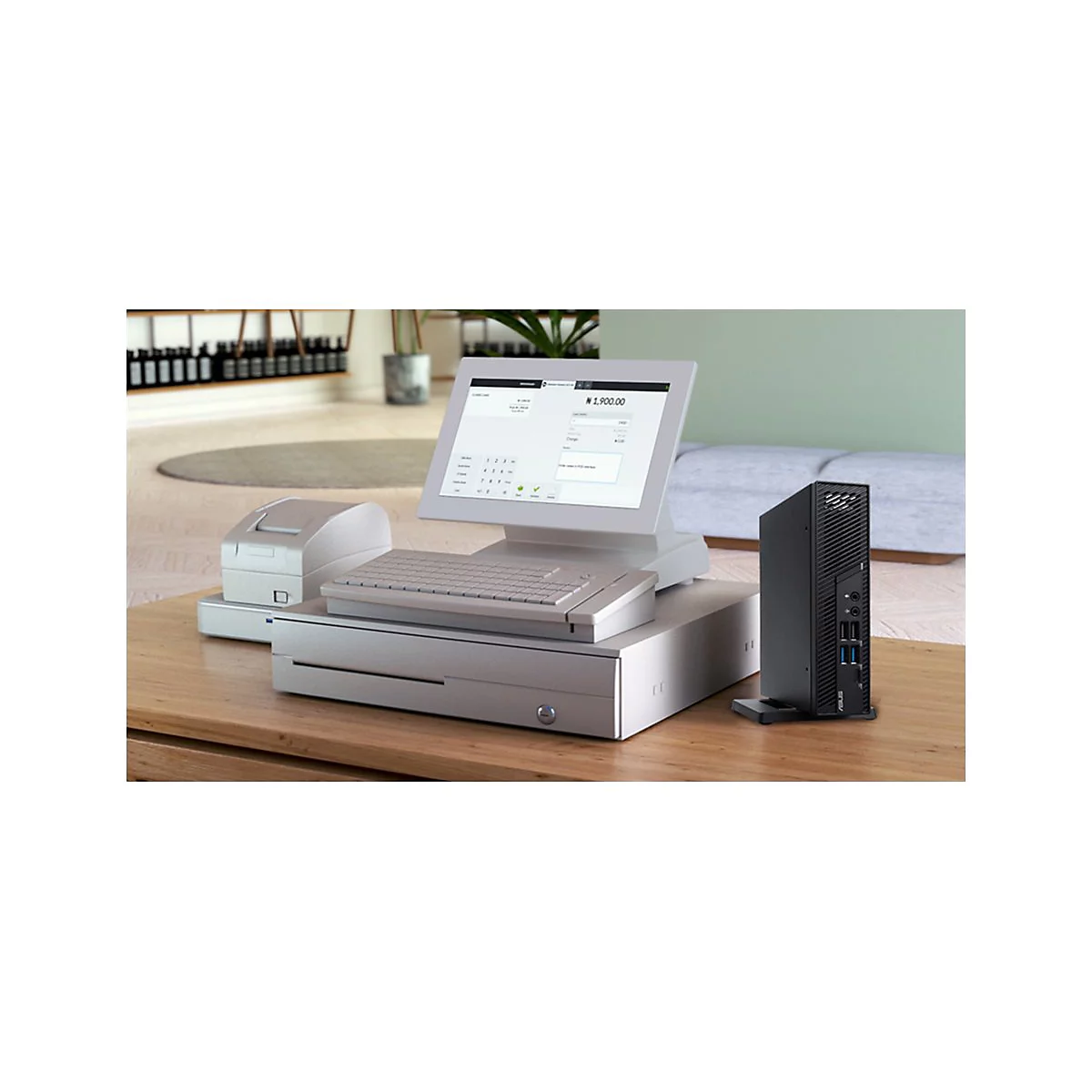 Ein Kassensystem steht auf einem Holztisch. Darauf befinden sich ein Bildschirm, eine Tastatur, eine Kasse, ein Drucker und ein schwarzer PC.