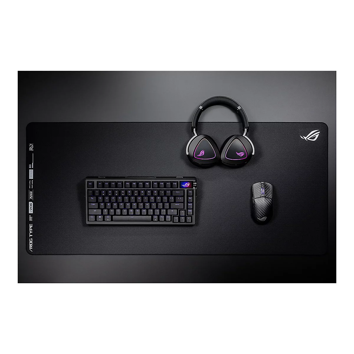 Schwarzes Gaming-Set mit Tastatur, Maus und Headset auf einer großen Mausmatte mit Logo.
