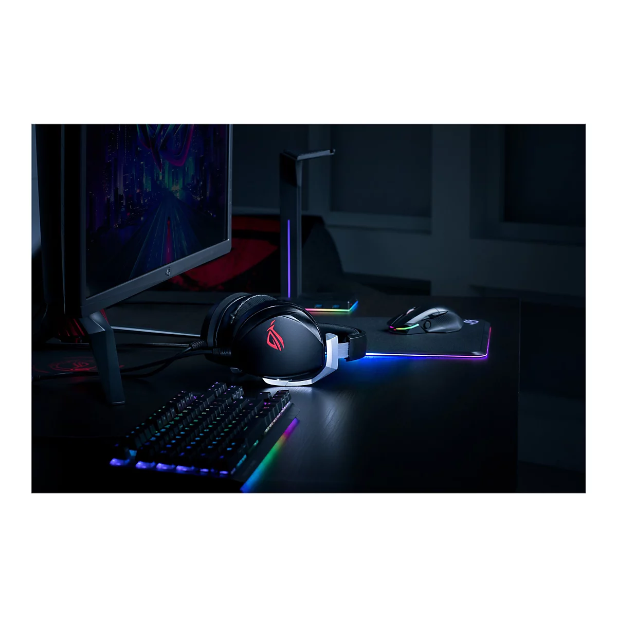 Gaming-Setup mit KopfhÃ¶rern, Tastatur, Maus und Monitor auf einem Schreibtisch. Beleuchtung in Regenbogenfarben.