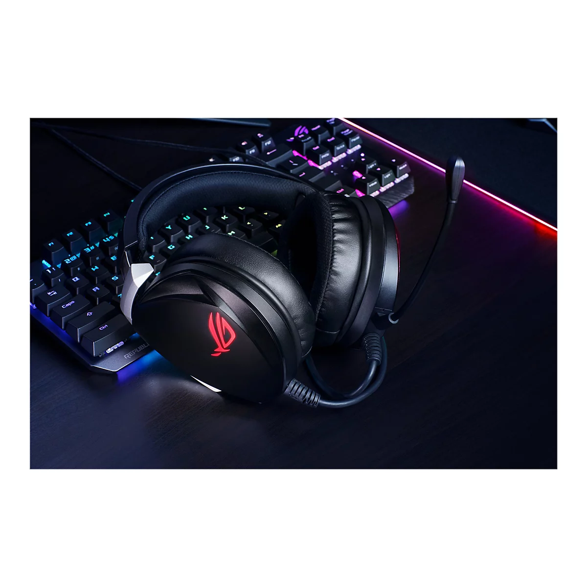 Schwarzes Gaming-Headset auf einer dunklen TischoberflÃ¤che, daneben eine beleuchtete Tastatur. Auf dem Headset ist das ROG-Logo zu sehen.