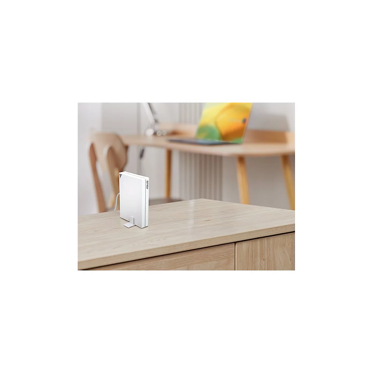 Weißes ASUS-Gerät steht auf einem Holzschreibtisch. Im Hintergrund ein Laptop.