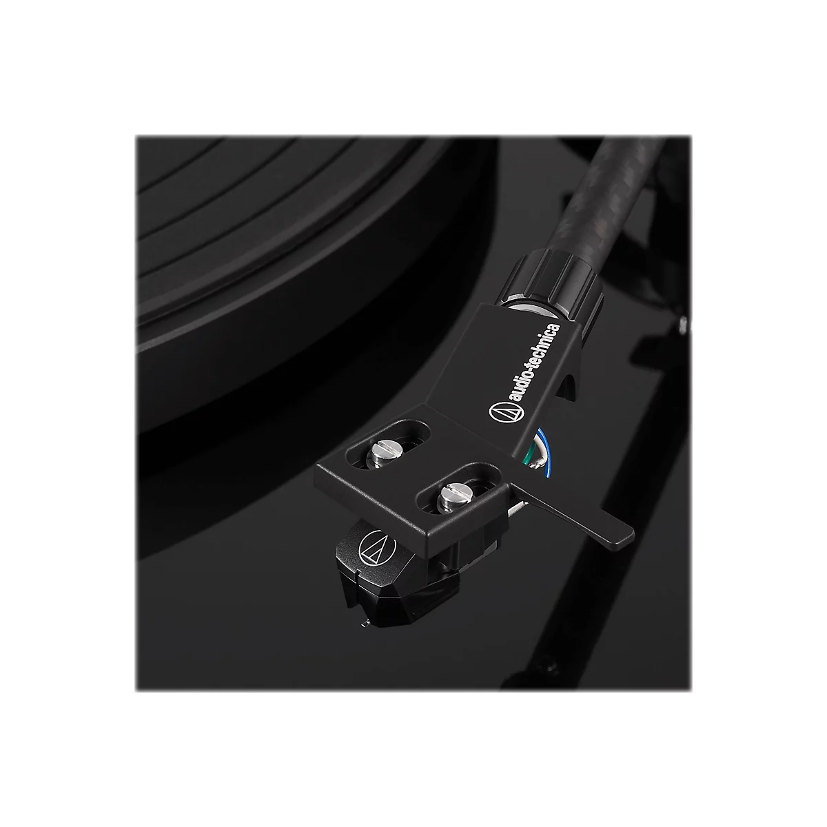 Nahaufnahme des Tonabnehmersystems eines schwarzen Audio-Technica Plattenspielers auf glänzender Oberfläche.