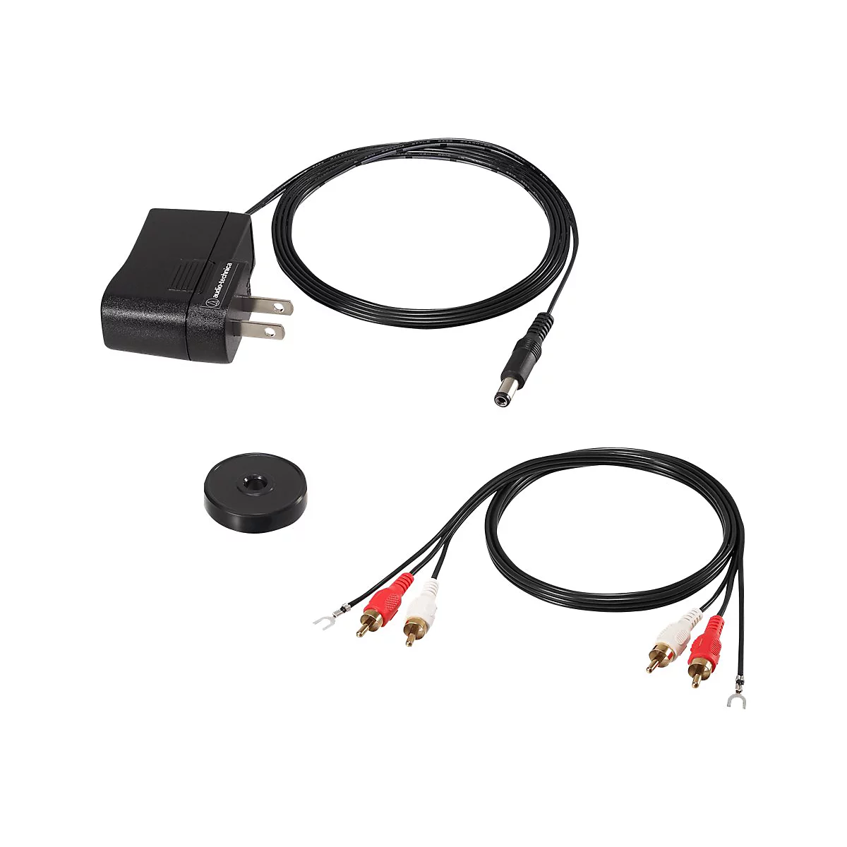 Zubehör für einen Plattenspieler, bestehend aus Netzteil, Cinch-Kabel, schwarzer Puck, weißem und rotem Kabel. Auf weißem Hintergrund.