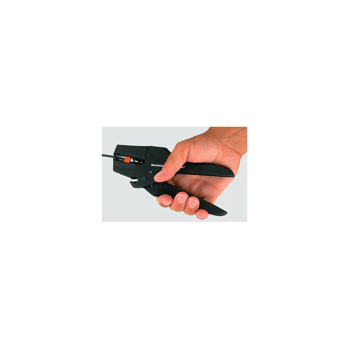 Hand houdt een zwarte draadstripper vast; een draad wordt gestript.