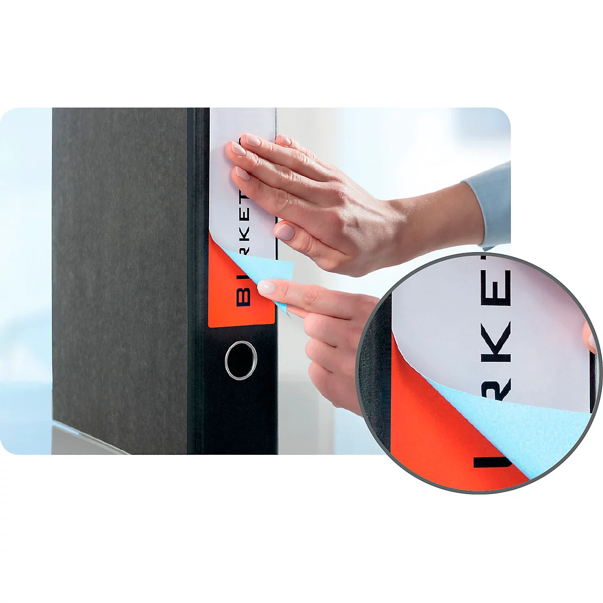 A person is sticking a label on a black folder. The label is half peeled off, showing the inscription "BIRKET".