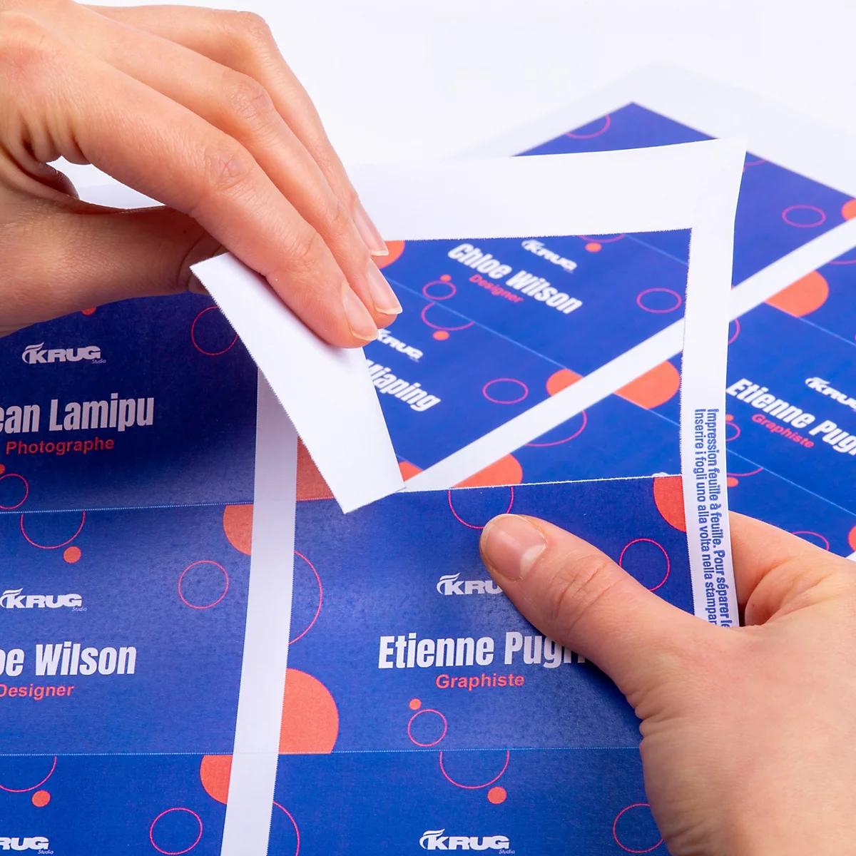 Handen maken een bedrukt visitekaartje los van een A4-vel, tekst: Eenvoudig los te maken, hoogwaardig 190 g papier.