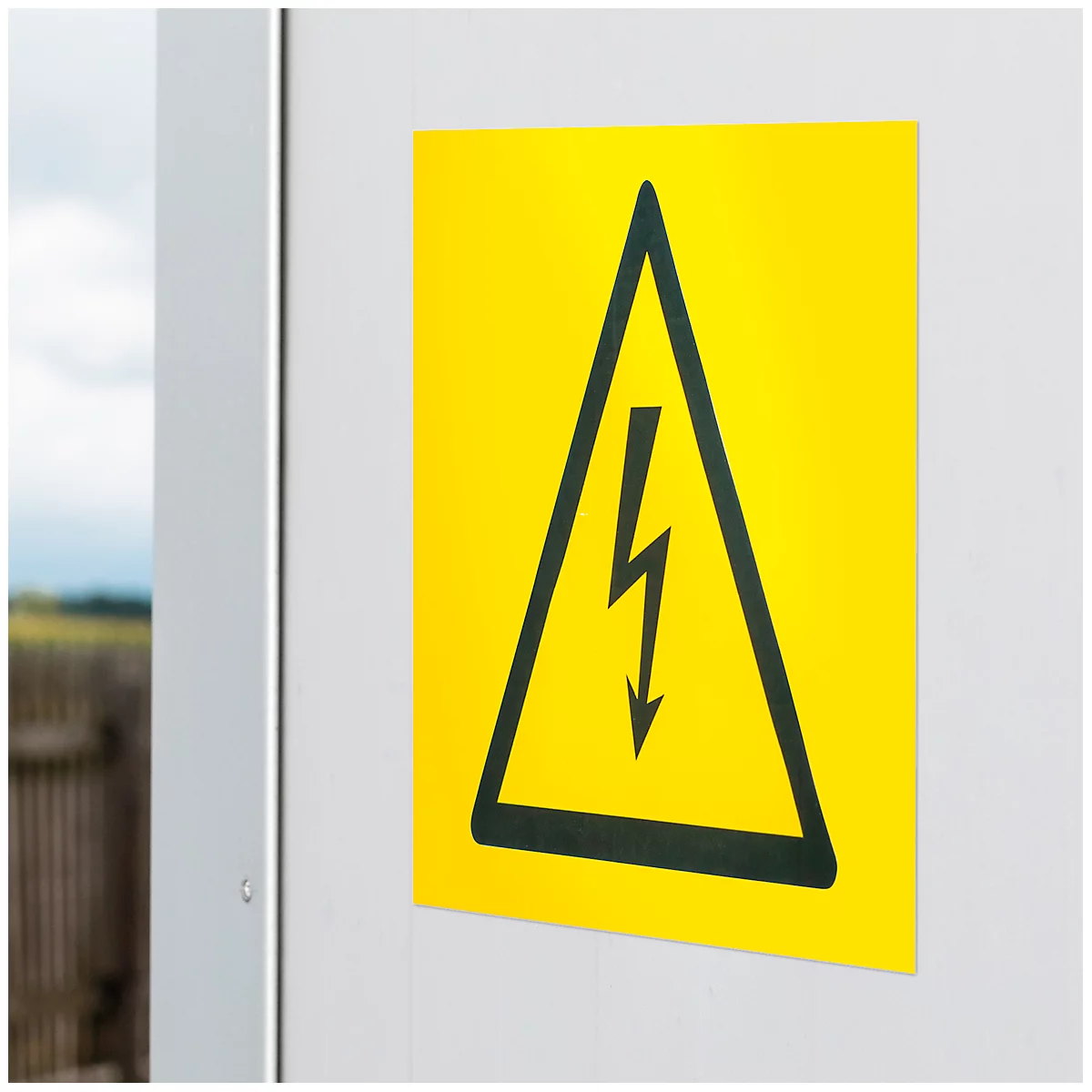 Yellow warning sign with black lightning bolt in a triangle on a white wall.