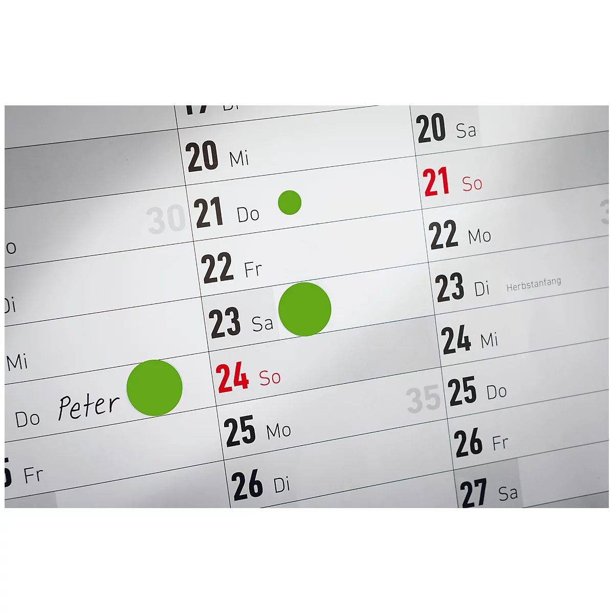Nahaufnahme eines Kalenders, mit grünen Kreisen auf den Daten 21, 23 und 24 markiert.