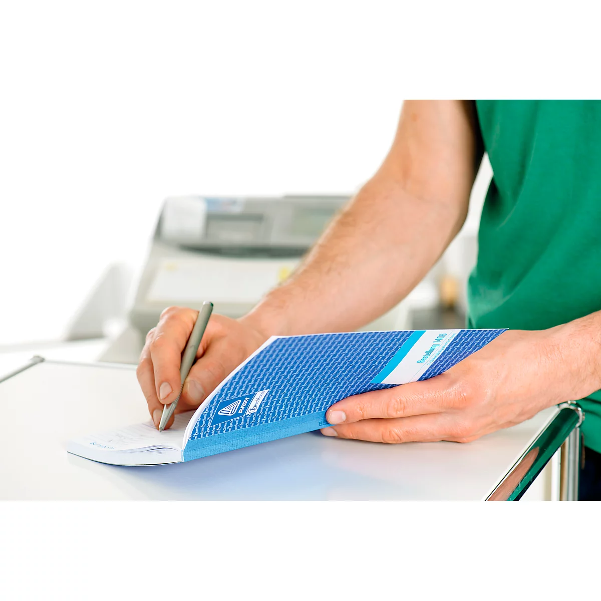 Person writing on a check with a pen. The check's side is blue and has a pattern.