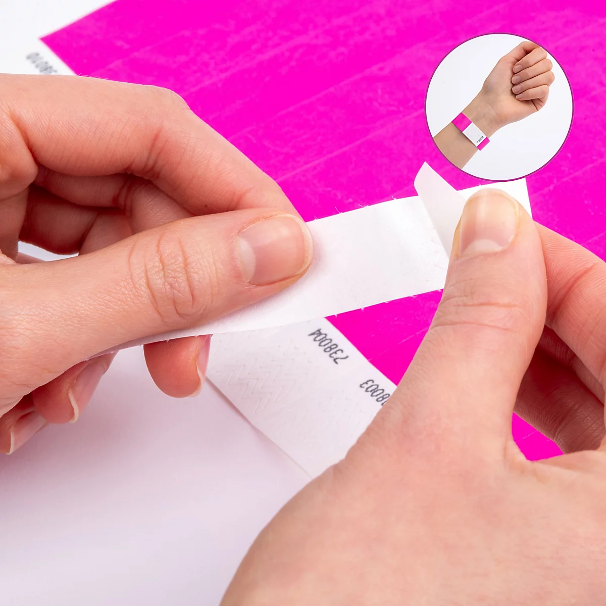 Handen trekken een witte beschermstrip van een roze, fraudebestendige polsbandje.