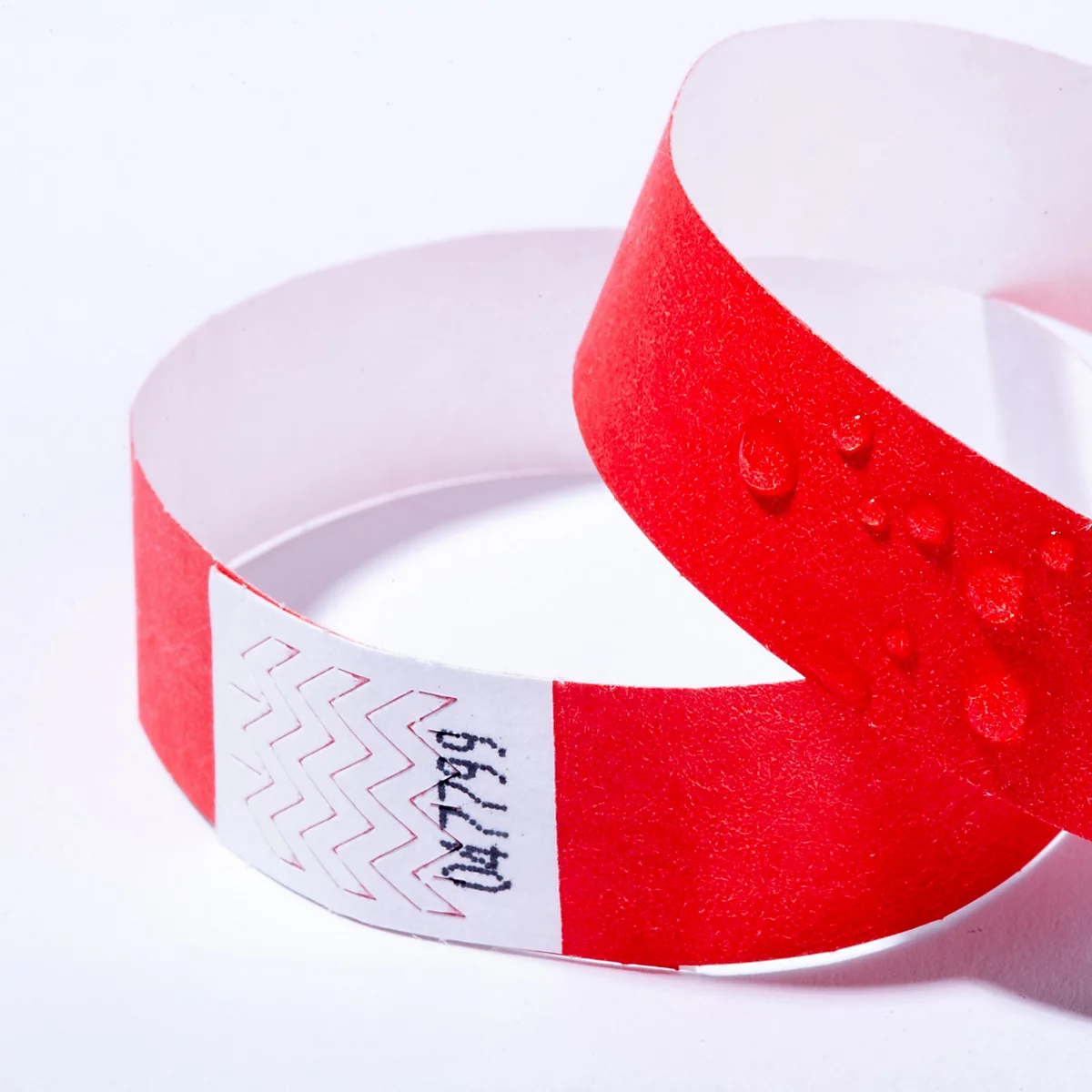 Ein rotes Einlassband aus Papier mit Wassertropfen und der aufgedruckten Nummer 047799.
