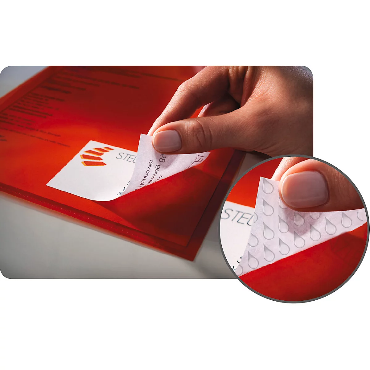 Close-up of hand peeling a sticker from a red envelope. In detail: water droplet pattern.