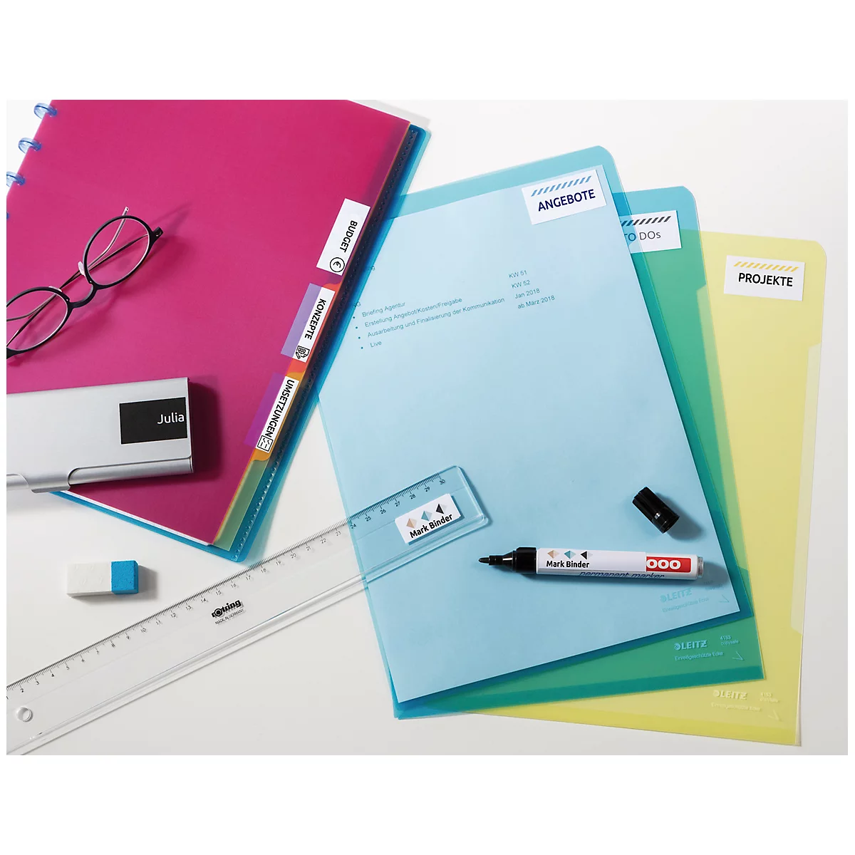 Overhead view of office supplies: folders, pens, ruler, eraser, glasses.