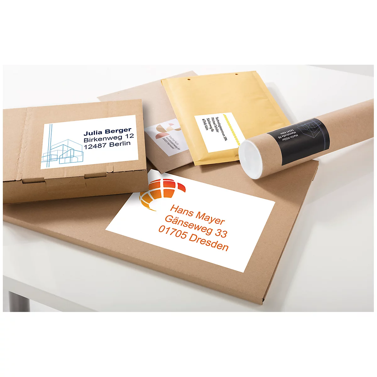 Various packages and envelopes, labeled with address labels, are lying on a white surface.