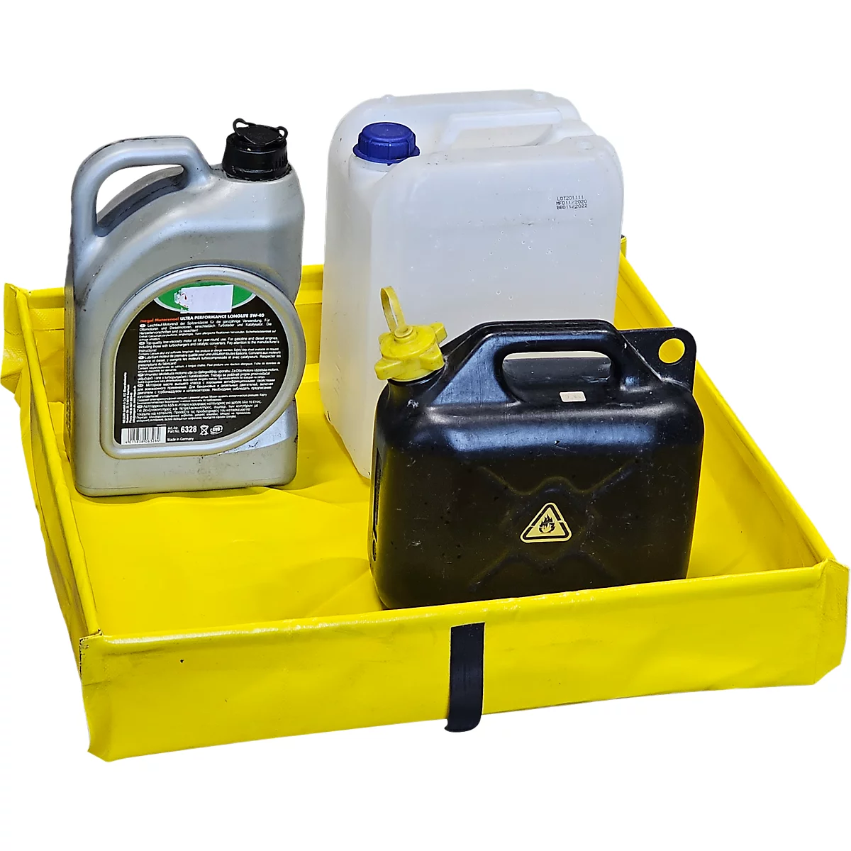 Des bidons et des bouteilles sont posés sur un bac de rétention jaune. Un bidon noir avec un panneau d'avertissement, un bidon gris et un bidon blanc.