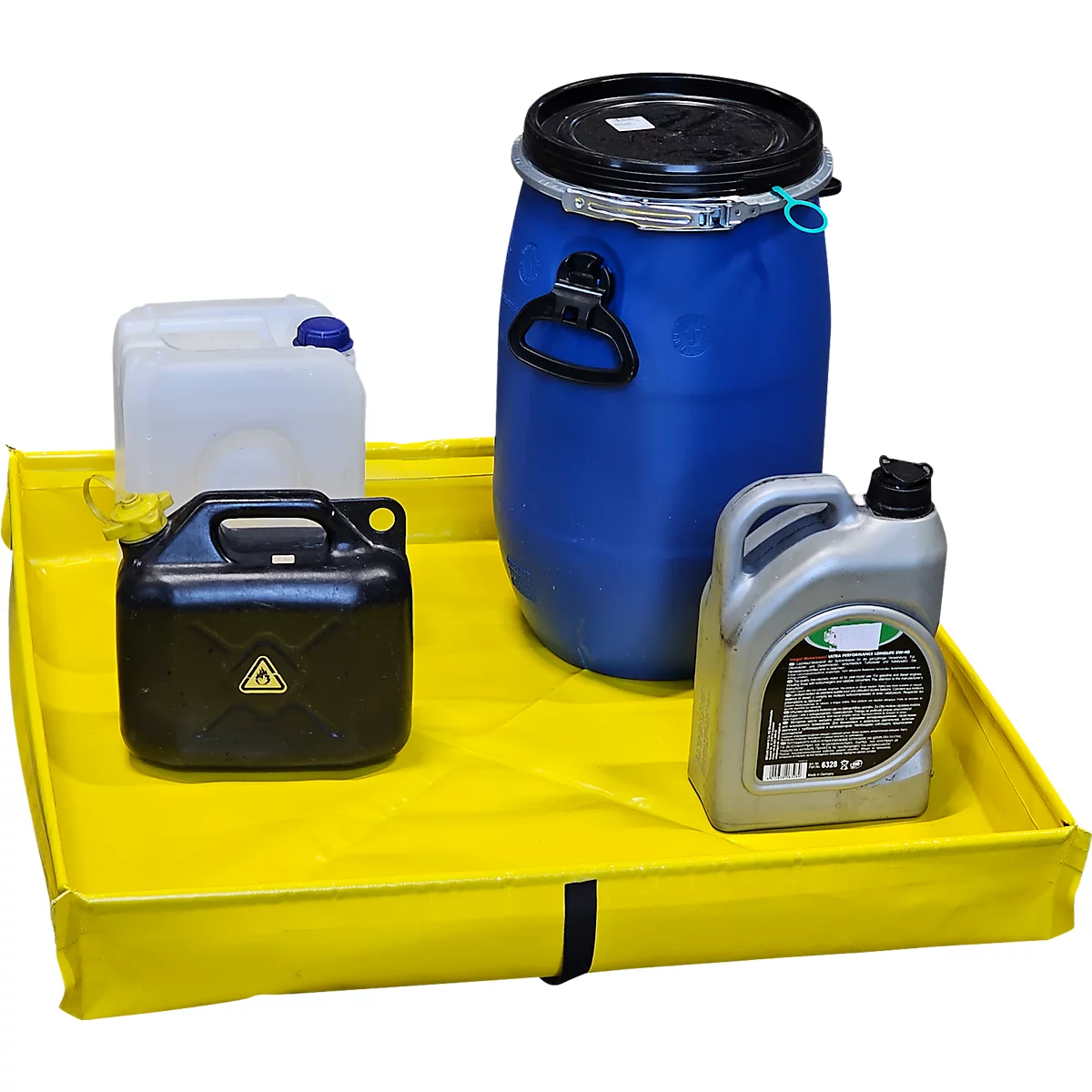 Bac de rétention jaune avec différents contenants ; tonneau bleu, bidon noir, bidon argenté.