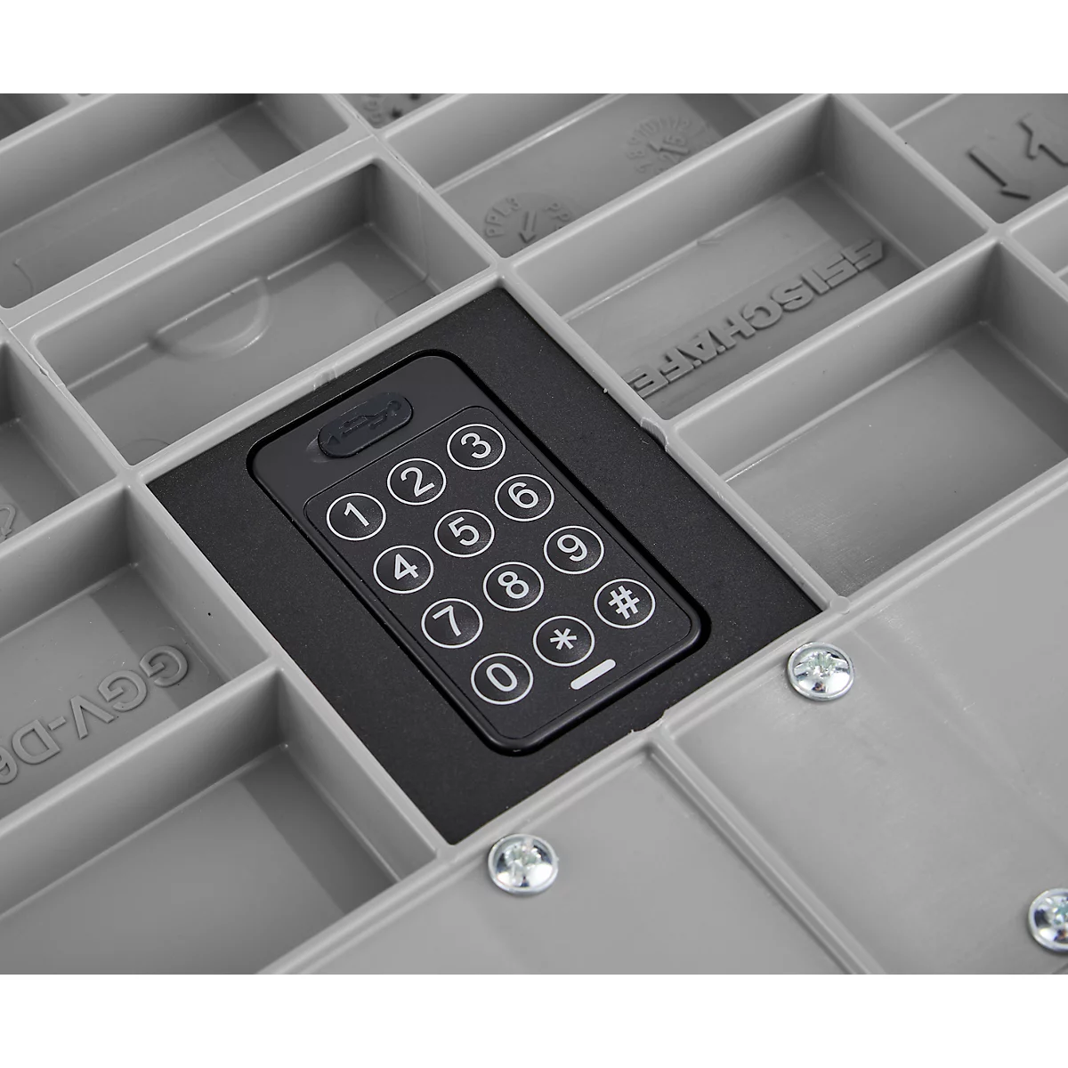 Vue détaillée d'une boîte en plastique grise avec un clavier noir avec des chiffres et des symboles. La boîte comporte plusieurs compartiments.