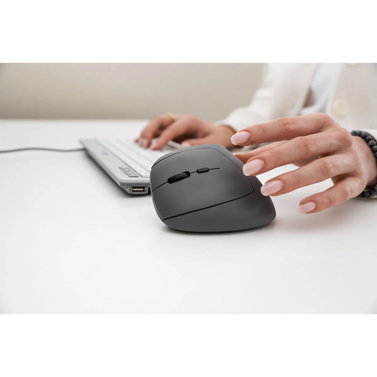 Eine Frau benutzt eine ergonomische Maus und Tastatur; der Fokus liegt auf der Hand am Maus.