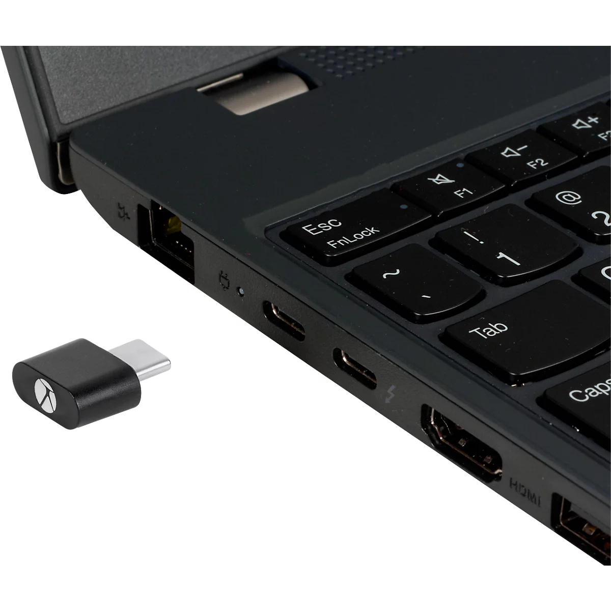 Ein schwarzer USB-C-Adapter neben einem Laptop. Der Adapter und die Laptop-Seite sind im Detail zu sehen, mit Tastatur und Anschlüssen.