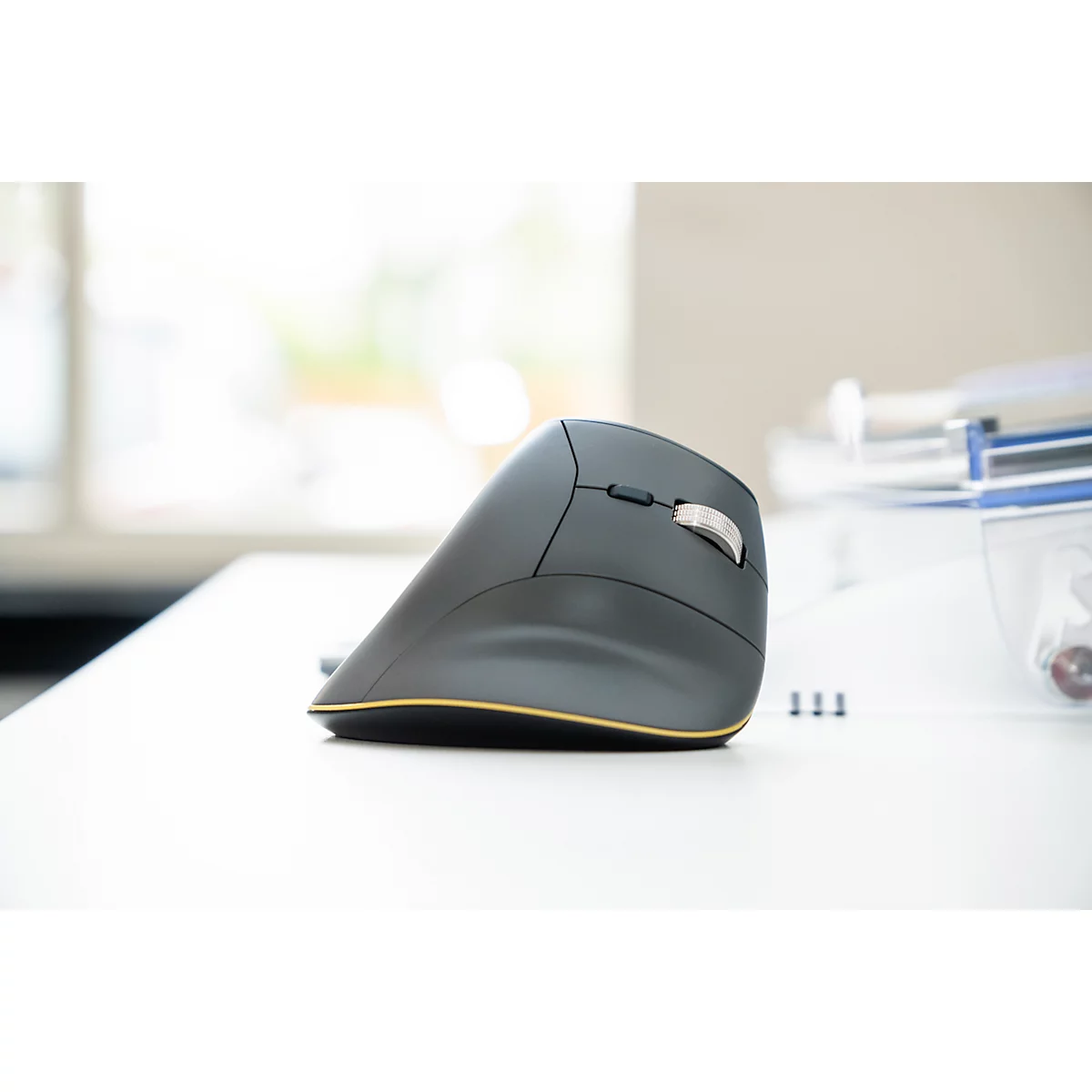 Ergonomische Computermaus in Grau mit gelben Akzenten auf weißem Tisch.
