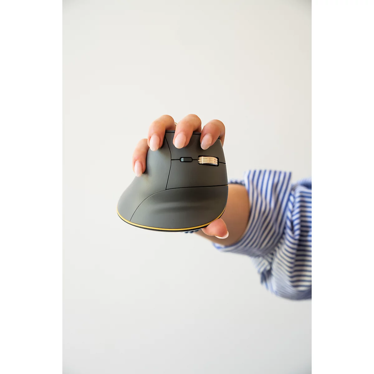 Eine Hand hält eine graue ergonomische Maus mit goldenem Rand. Im Hintergrund ein blau-weiß gestreiftes Hemd auf weißem Grund.