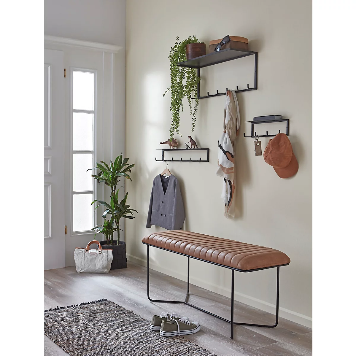 Hall d'entrée avec un banc, des porte-manteaux, des plantes et de la décoration. Des chaussures sont visibles au premier plan.