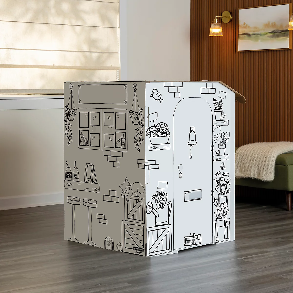 Une maison en carton avec des illustrations noir et blanc d'une façade. Un chat est couché sur une boîte.